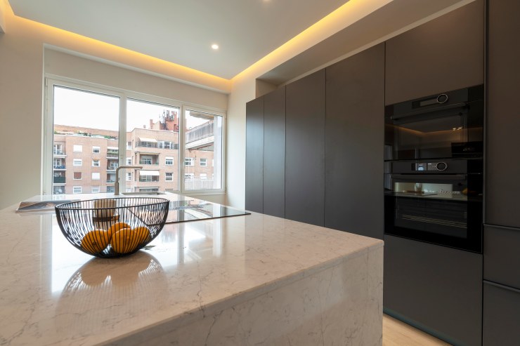 Imagen profesional de cocina gourmet con isla y vistas al jardín en villa de La Finca, Pozuelo.